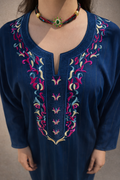 Close-up of the dense gold embroidery and shimmering crystals on the deep navy U-neckline.