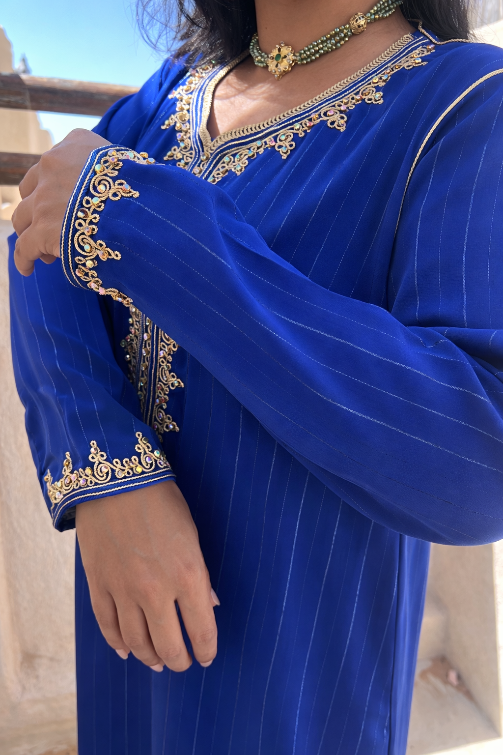 Detailed view of the handcrafted gold embroidery on the front panel and neckline of the Whispers of Azure kaftan.