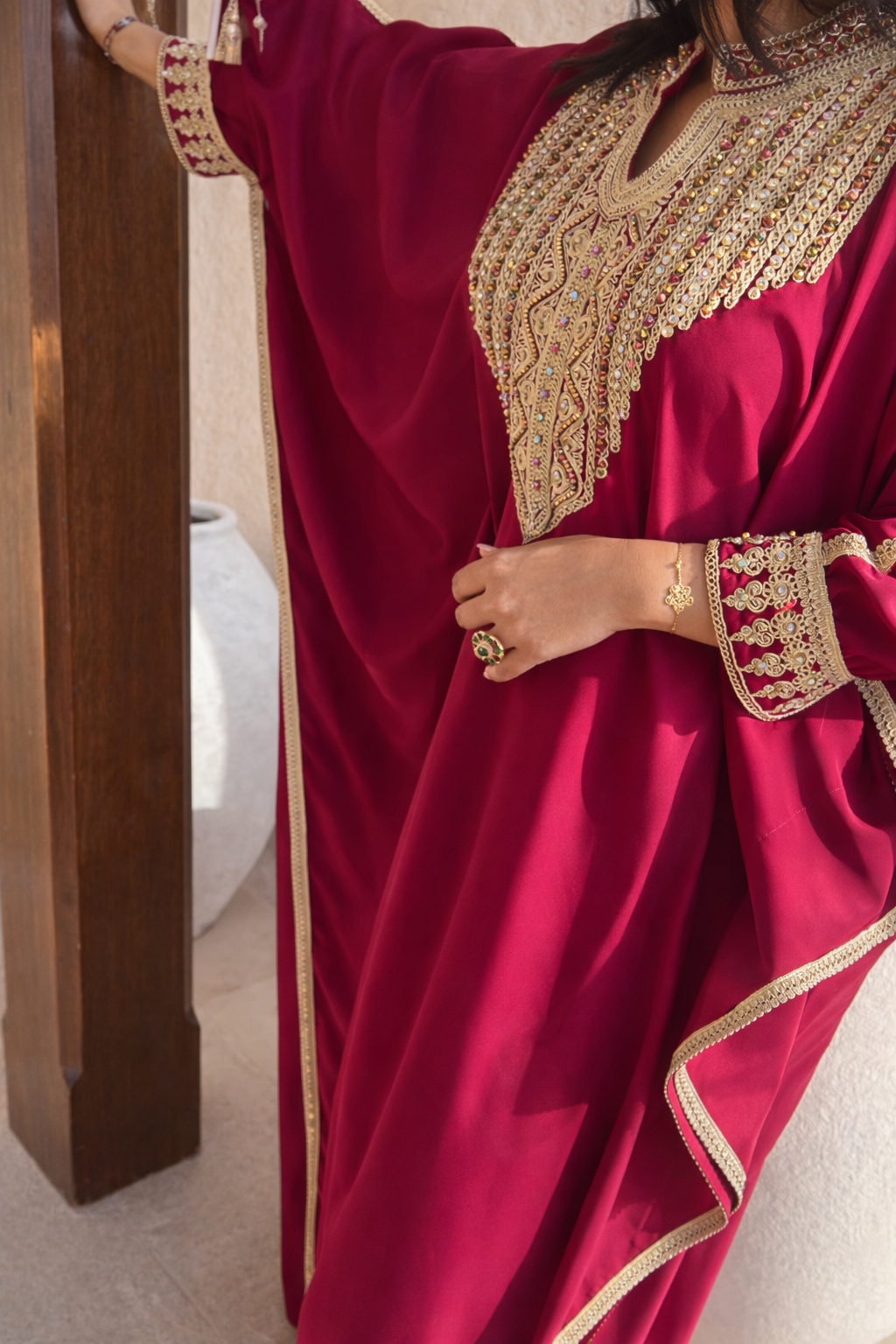 Detailed view of the fuchsia kaftan sleeve featuring gold piping and crystalline embroidery by Maison Nelya.