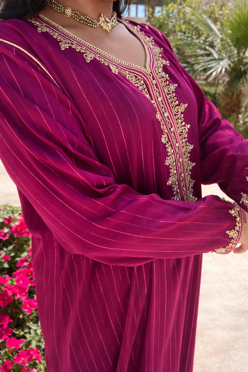 Detailed view of the intricate gold embroidery cascading down the front of the amaranth kaftan.