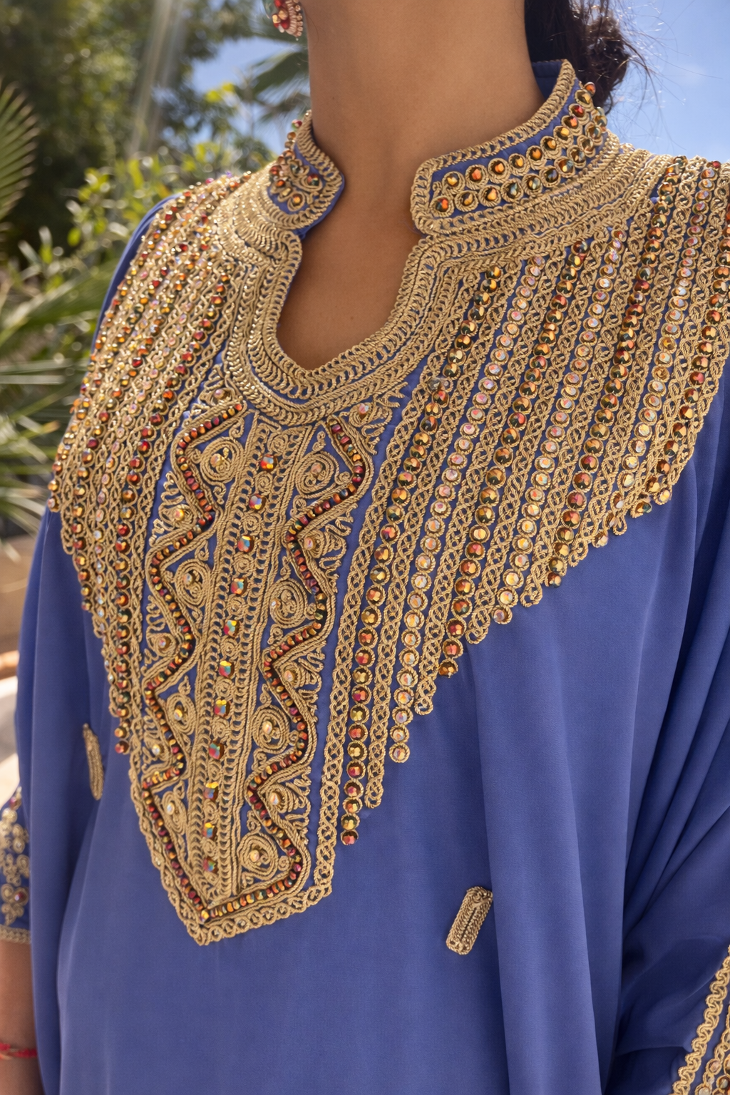 Close-up of the intricate gold thread and colorful crystal embroidery on the blue Maison Nelya kaftan neckline.