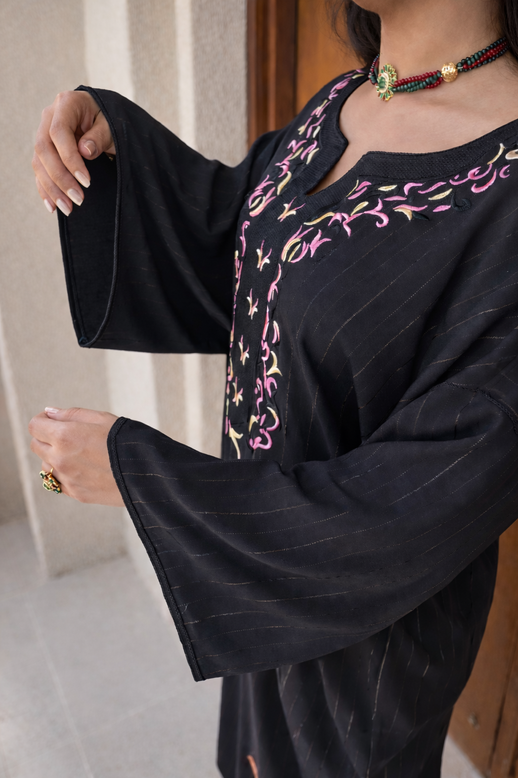 Detailed view of the artisanal gold thread-work on the wide butterfly sleeves of the Moonlit Noir Kaftan.