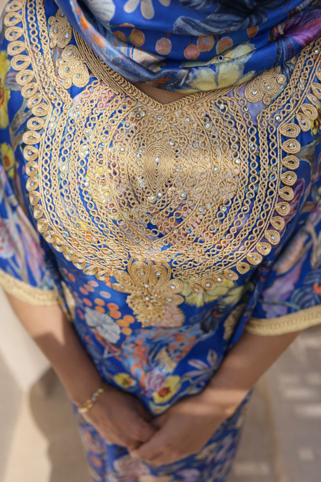 Close-up of the gold embroidery and crystals over the intricate blue floral motifs of the Maison Nelya kaftan.