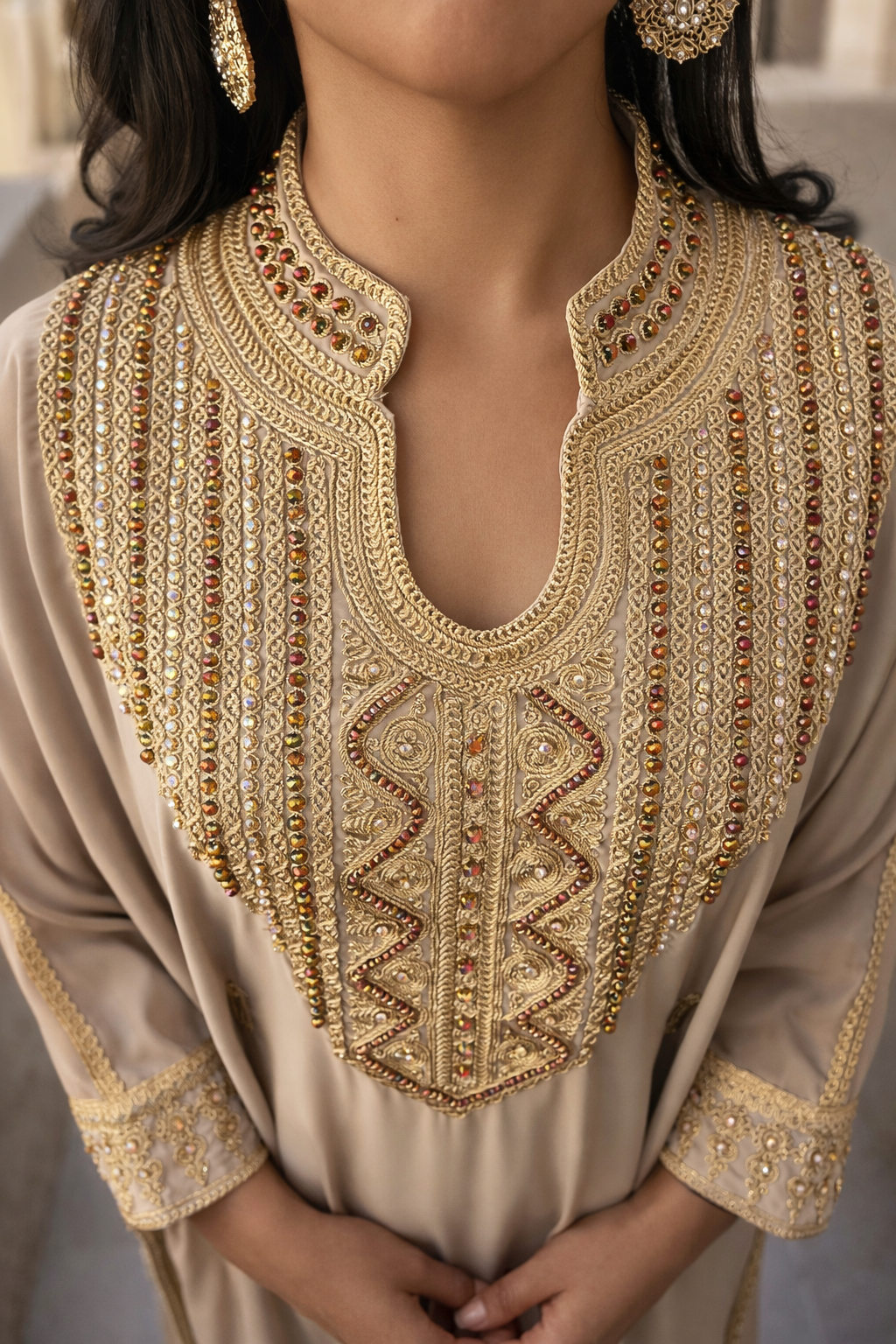 Close-up of the intricate gold embroidery and crystals on the floral blue fabric of the Desert Pearl Kaftan.