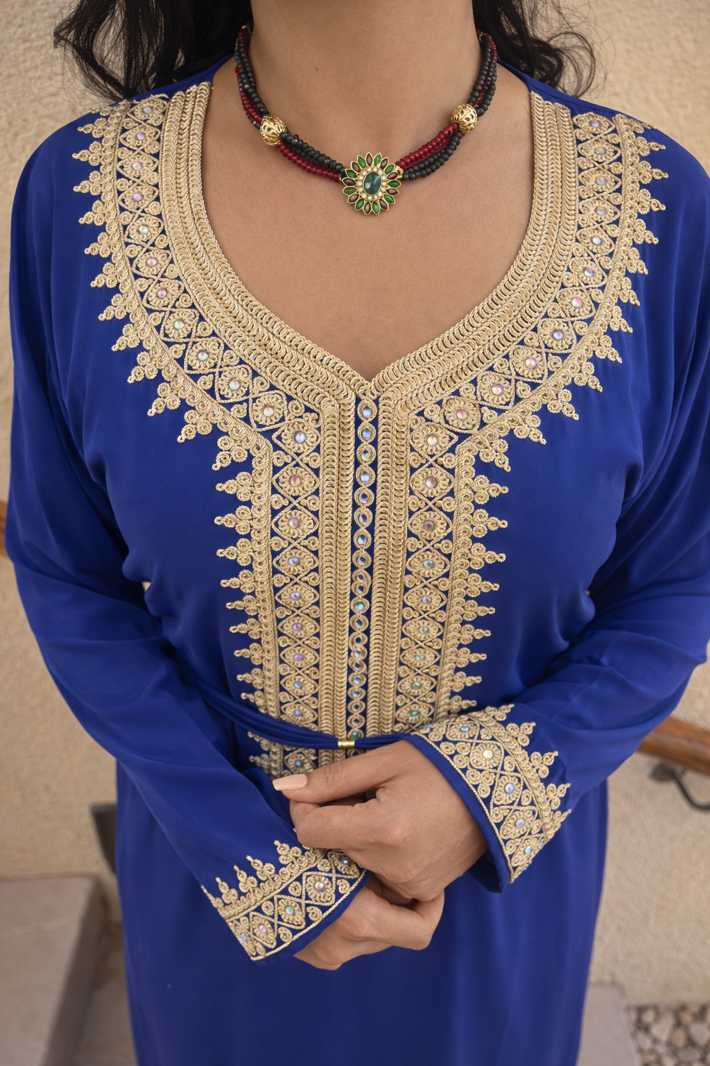 Close-up of the intricate gold thread and colorful crystal embroidery on the blue Maison Nelya kaftan neckline.