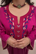 Close-up of the dense gold embroidery and shimmering crystals on the deep magenta U-neckline.
