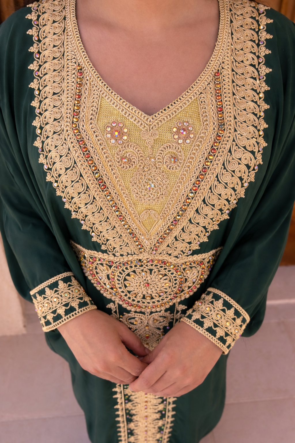 Detailed view of the intricate gold thread-work framing the neckline of the emerald green kaftan.