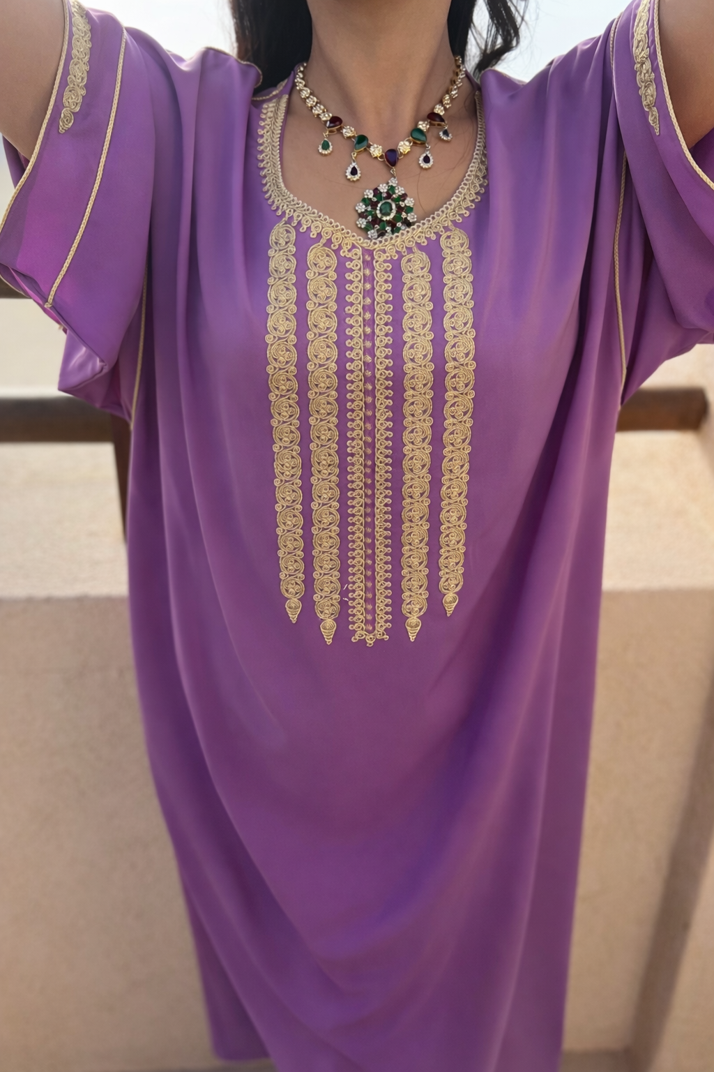 Close-up of the handcrafted gold embroidery and shimmering crystals on the emerald green kaftan neckline.