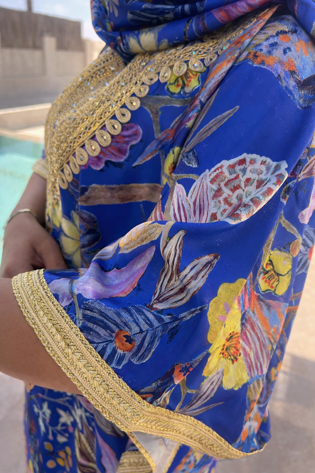 Detailed view of the gold thread-work on the wide butterfly sleeves of the Sapphire Blossom floral kaftan.