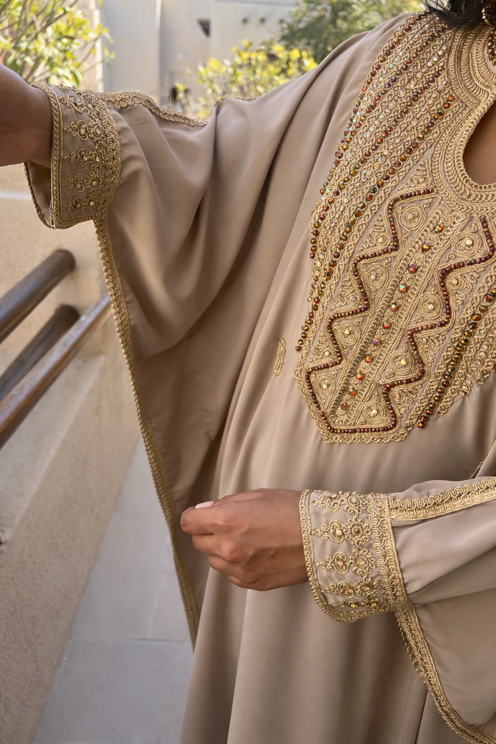 Detailed view of the gold thread patterns on the wide butterfly sleeves of the blue floral kaftan.