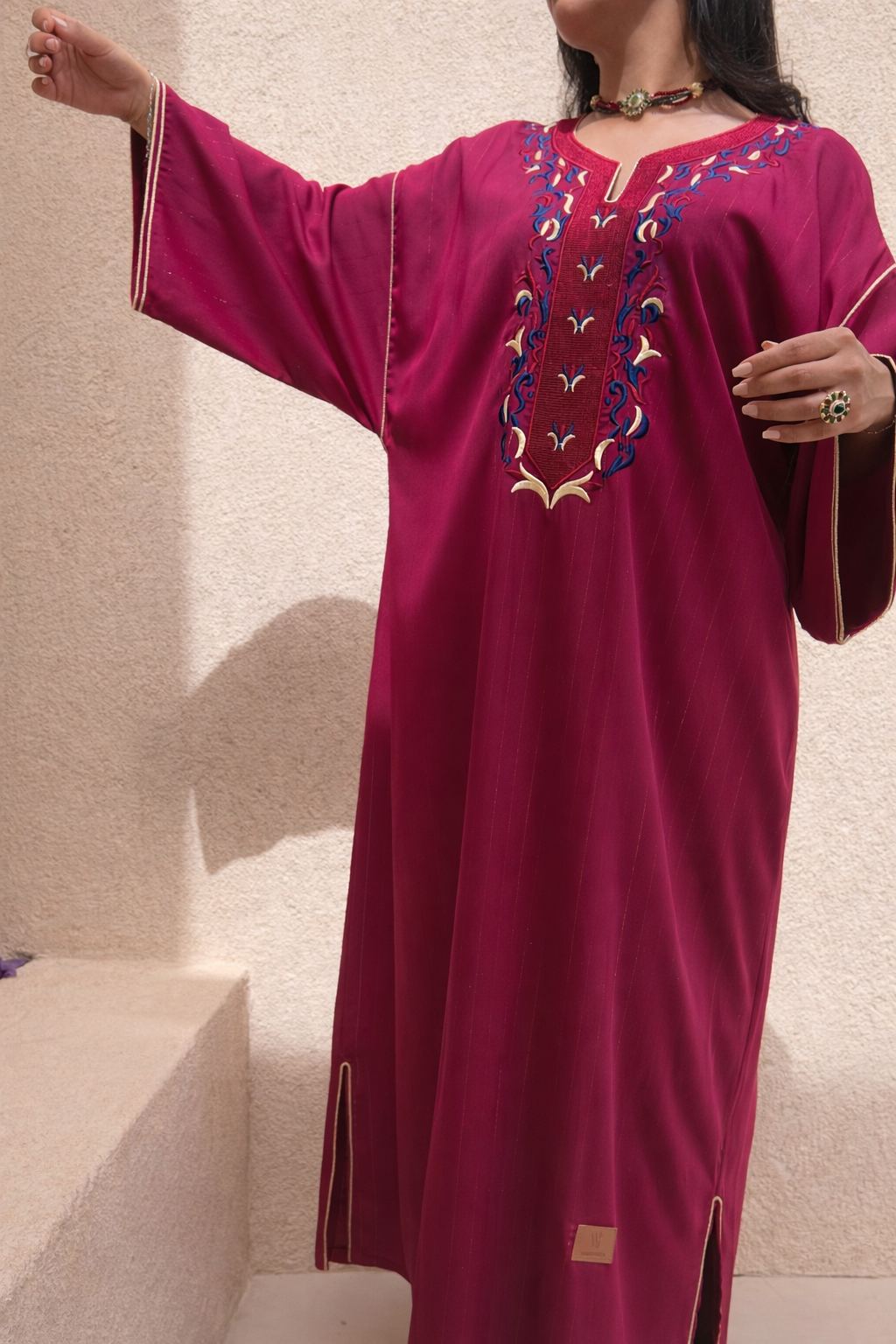 Full length view of the Maison Nelya Imperial Magenta Kaftan in deep magenta with gold embroidery.