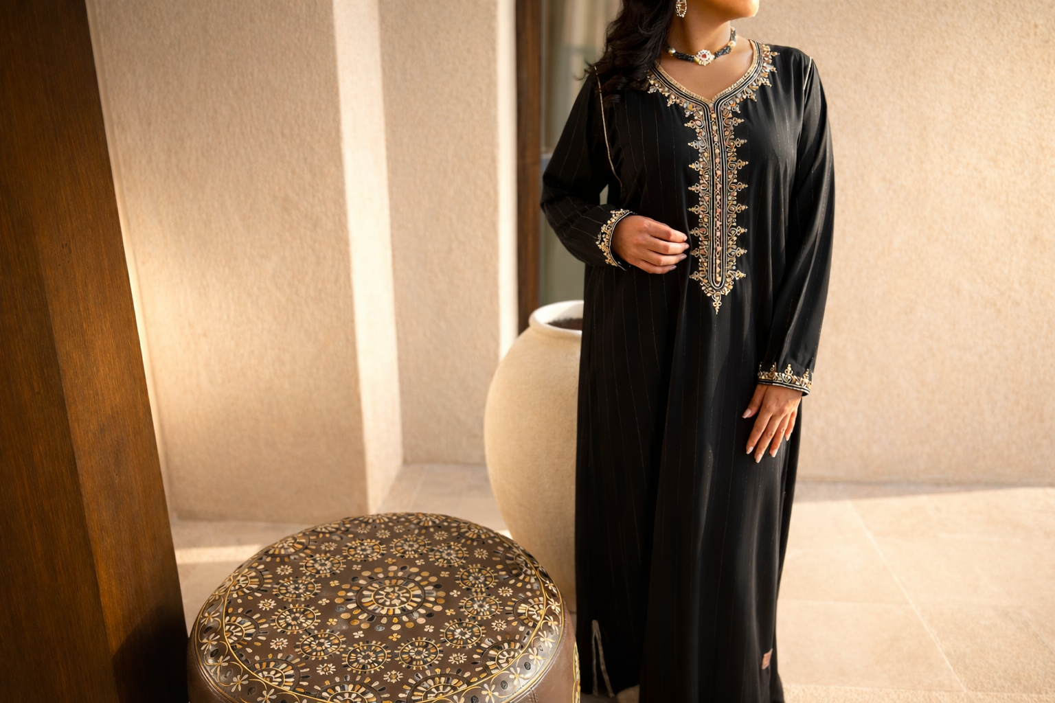 Standing view of the Maison Nelya Midnight Gold Abaya, featuring a black pinstripe fabric and gold embroidery.