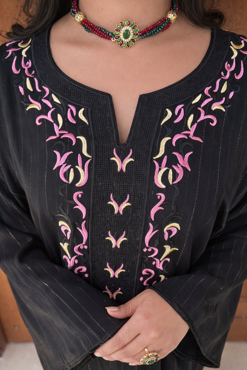 Close-up of the dense gold embroidery and hand-set crystals on the neckline of the black Moonlit Noir kaftan.