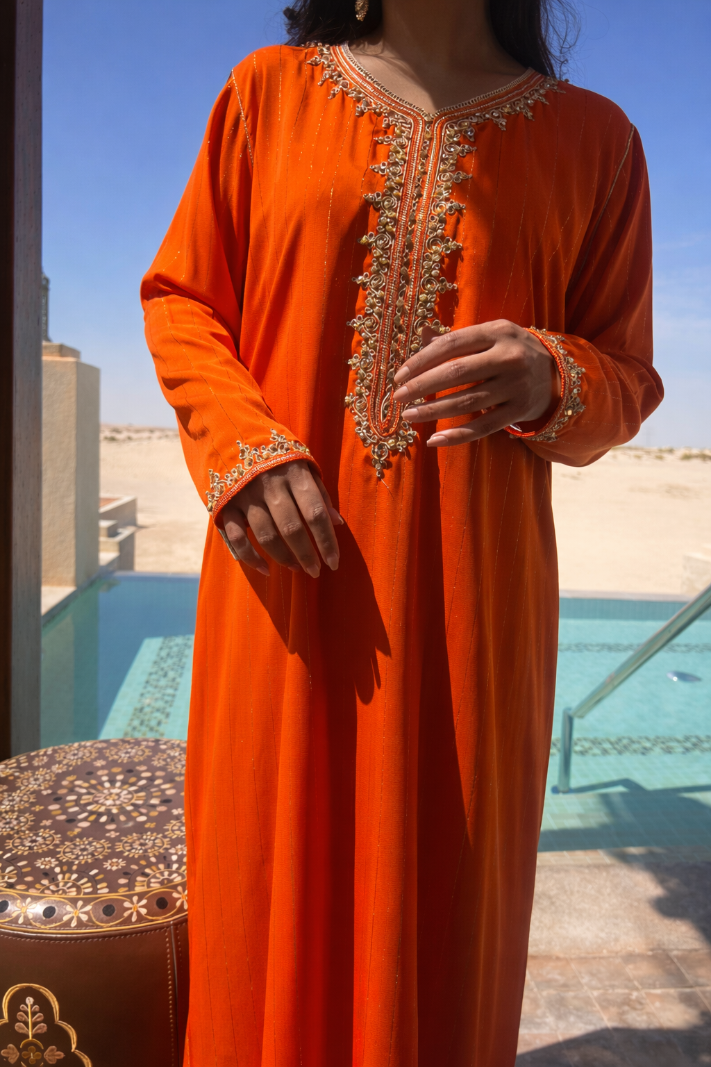 Full length view of the Maison Nelya Sunset Amber Kaftan in a vibrant orange hue with rich gold embroidery.